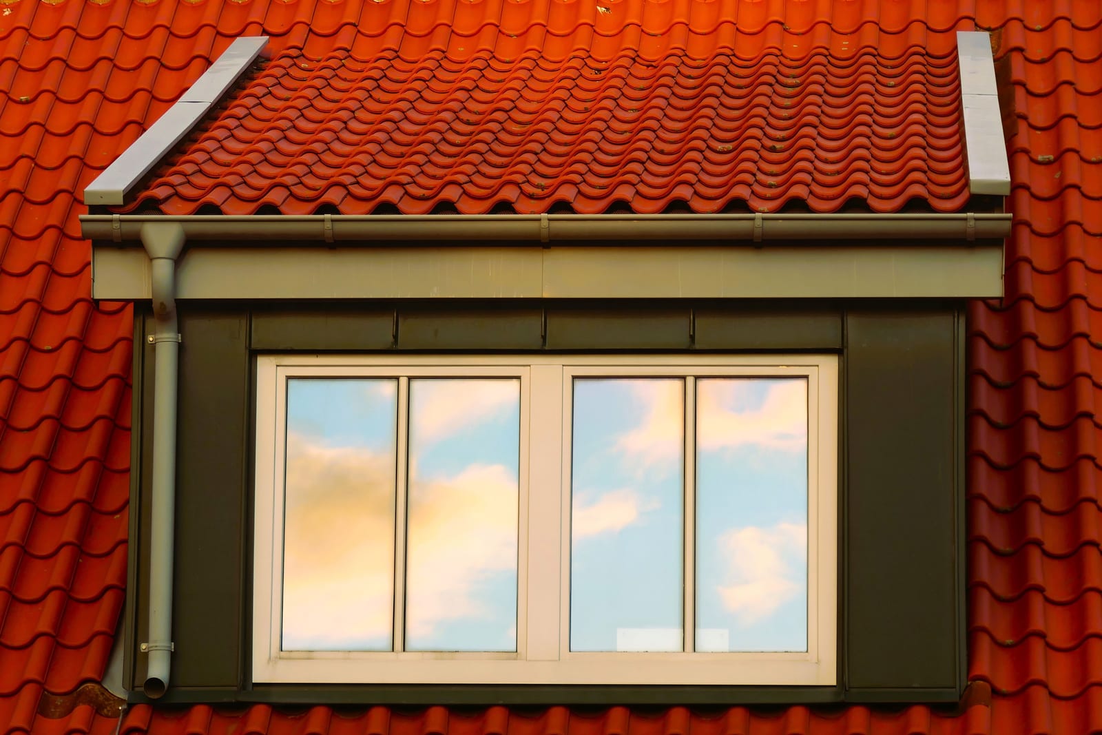 Red tile roof surrounding a dormer window, flashing transitions, and gutter